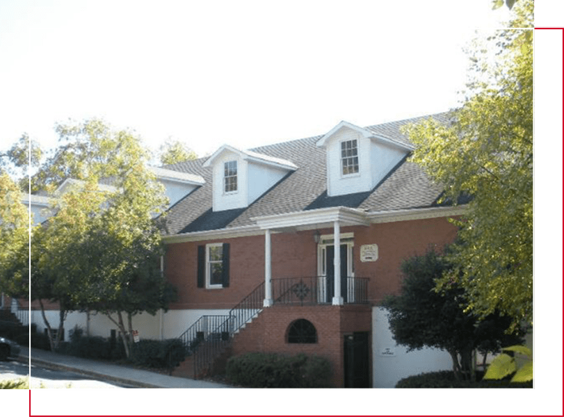 A red brick house with white trim and green shutters.