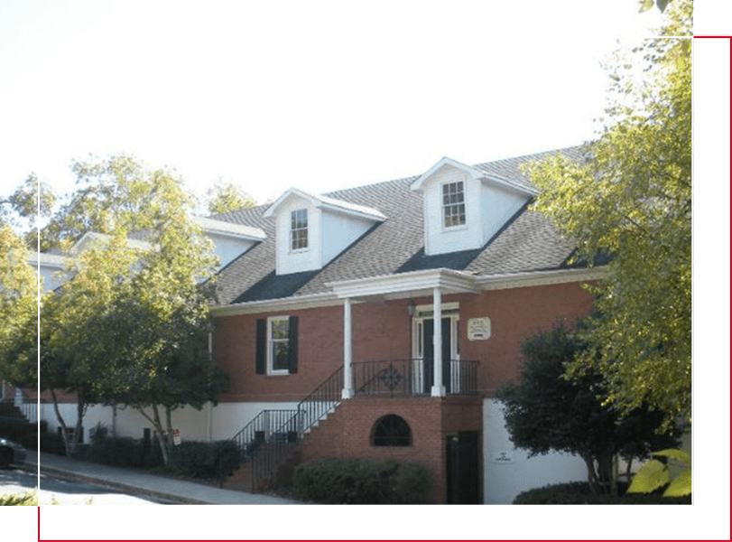 A red brick house with white trim and green shutters.