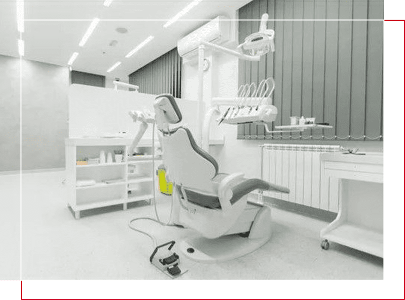 A dentist 's office with an empty chair and lights.