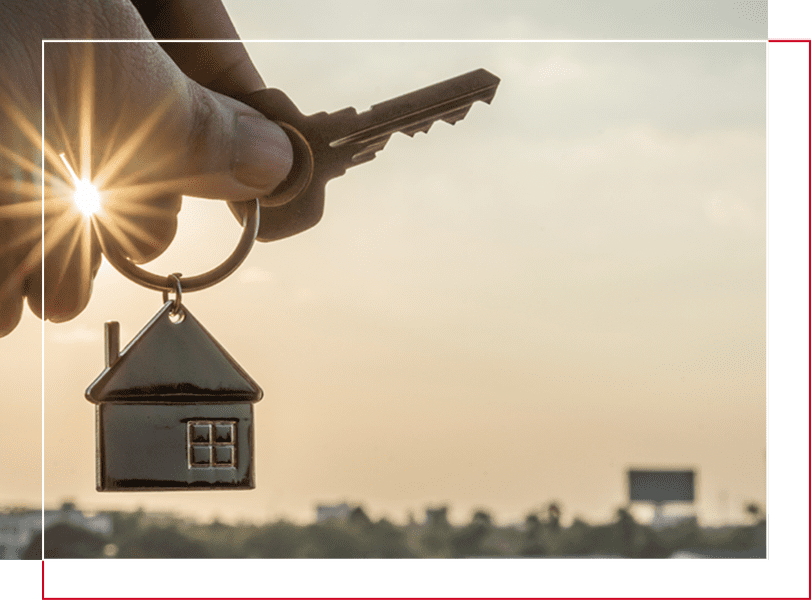 A hand holding keys with a house keychain hanging from it.