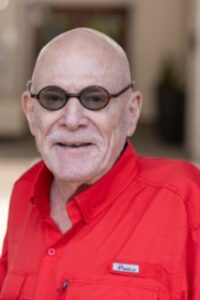 A man with glasses and bald head wearing red shirt.