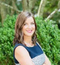 A woman standing in front of some bushes