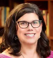 A woman with glasses smiling for the camera.