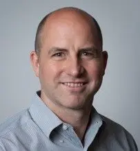 A man with bald head and wearing a blue shirt.